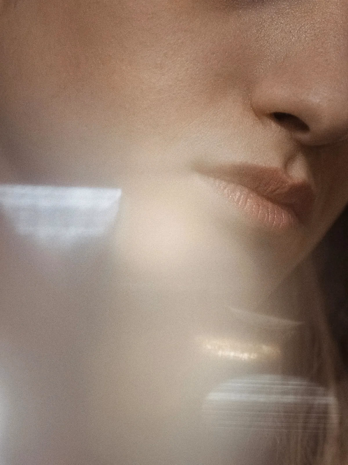 Primer plano de la mitad inferior de un rostro, tras un velo de luz difusa.
